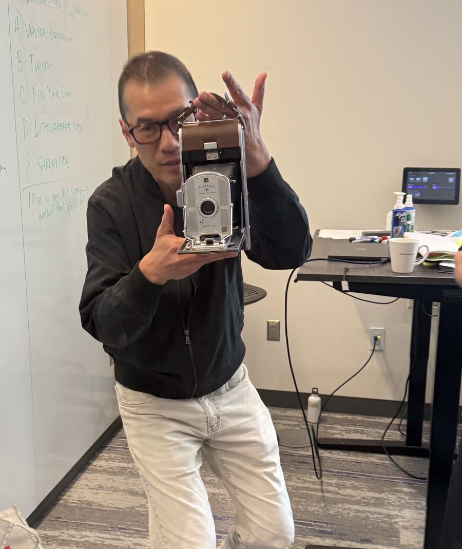 Chaki Ng holding up a vintage folding camera while teaching